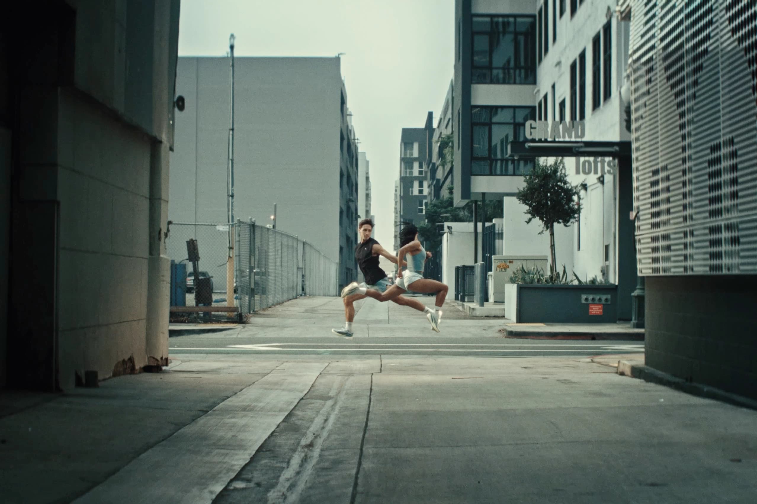 Person wearing Puma sneakers walking through an urban street with plants and city architecture