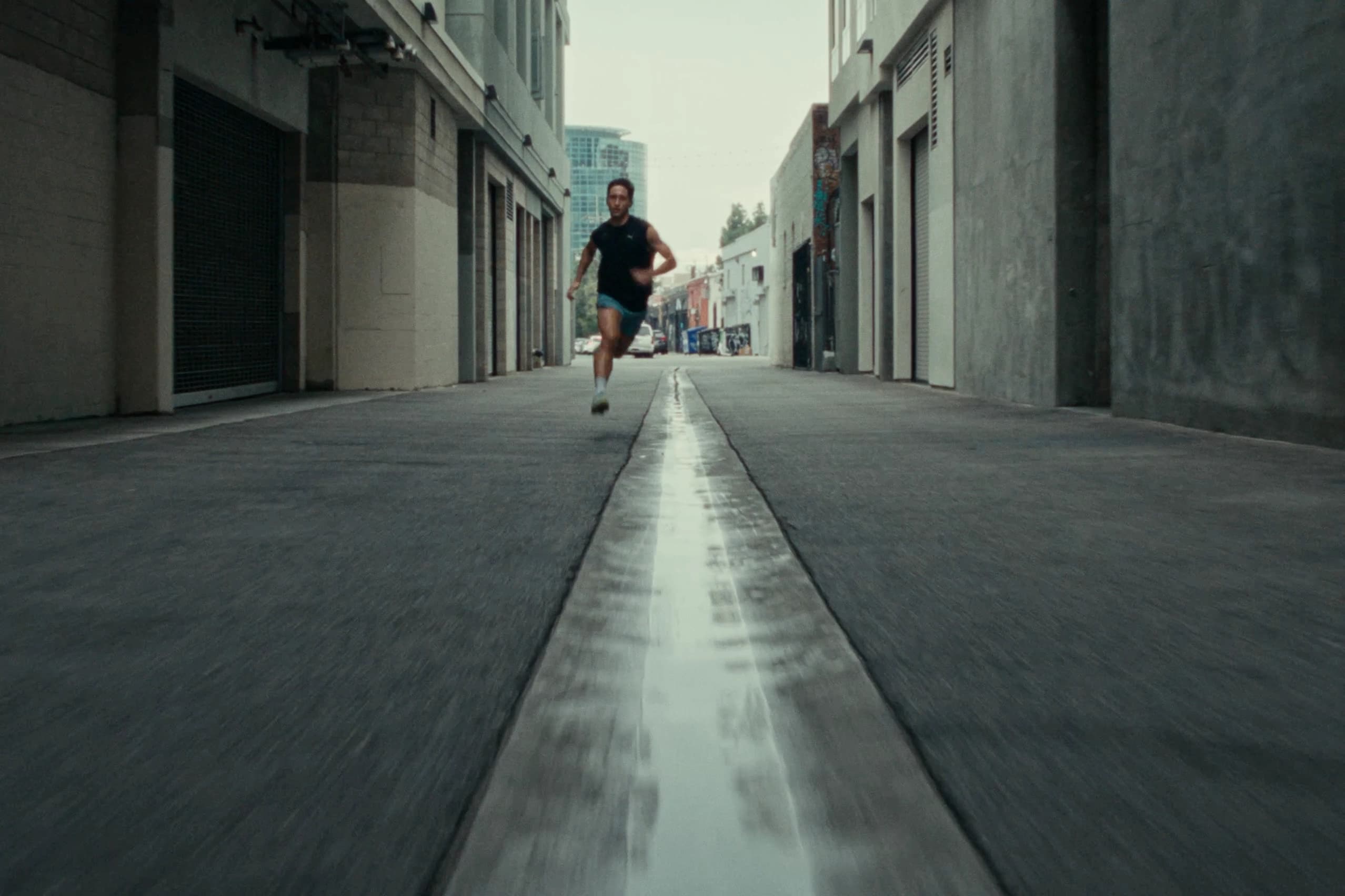 Person walking through a city alley wearing Puma gear, urban street photography